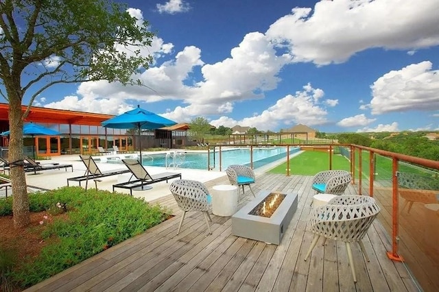 pool featuring an outdoor fire pit and a wooden deck