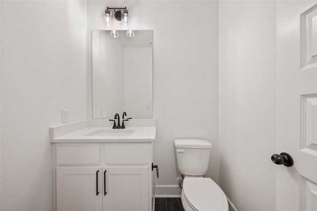 bathroom featuring toilet, baseboards, and vanity