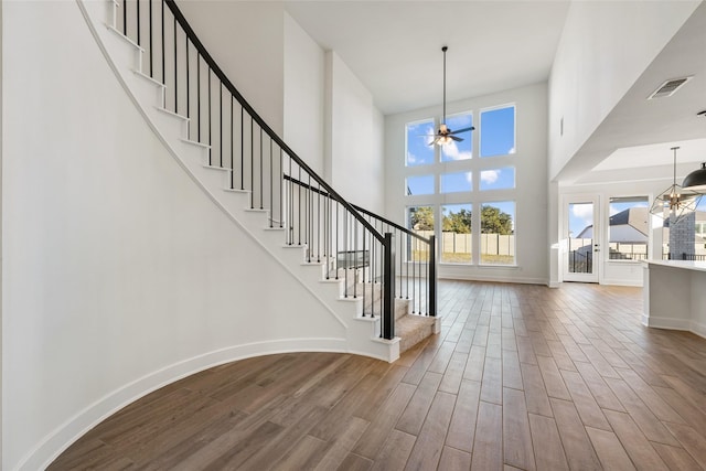 foyer entrance with a high ceiling and ceiling fan with notable chandelier