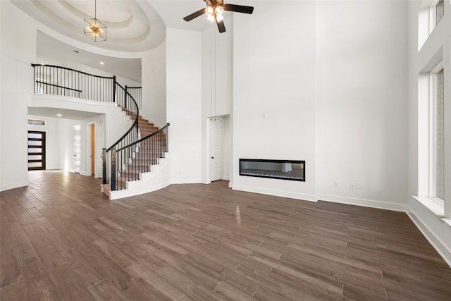 unfurnished living room featuring a tray ceiling, a towering ceiling, and a healthy amount of sunlight