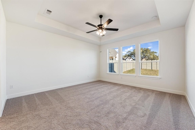 unfurnished room featuring baseboards, visible vents, a raised ceiling, and carpet flooring