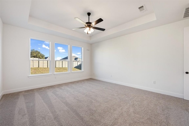 spare room with light carpet, a tray ceiling, and visible vents