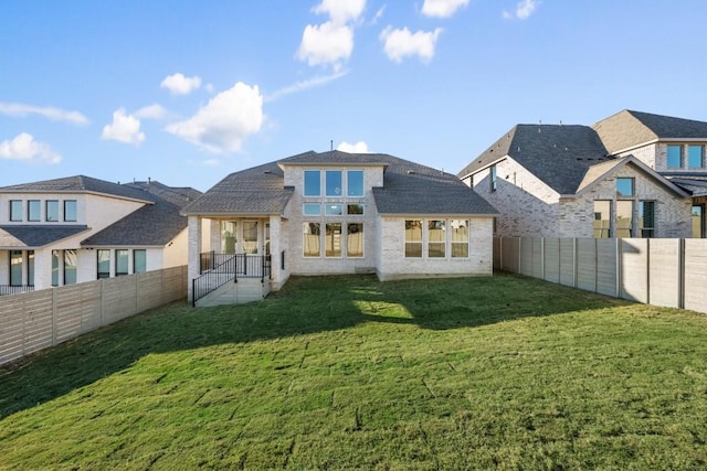 rear view of house with a fenced backyard and a lawn