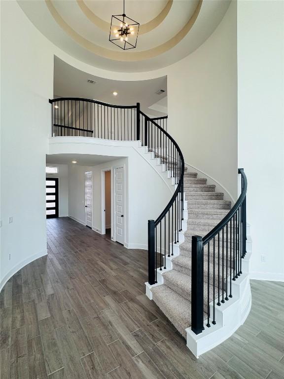 entrance foyer with stairs, baseboards, an inviting chandelier, and wood finished floors