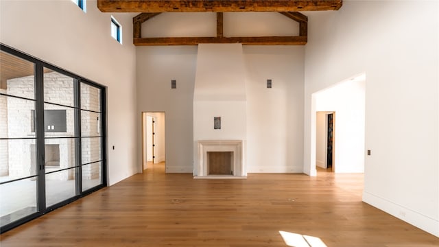 unfurnished living room featuring wood-type flooring, high vaulted ceiling, and beam ceiling