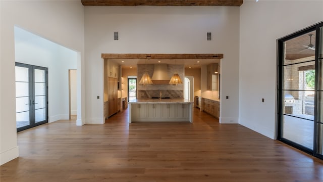 unfurnished living room with french doors, a towering ceiling, and a healthy amount of sunlight