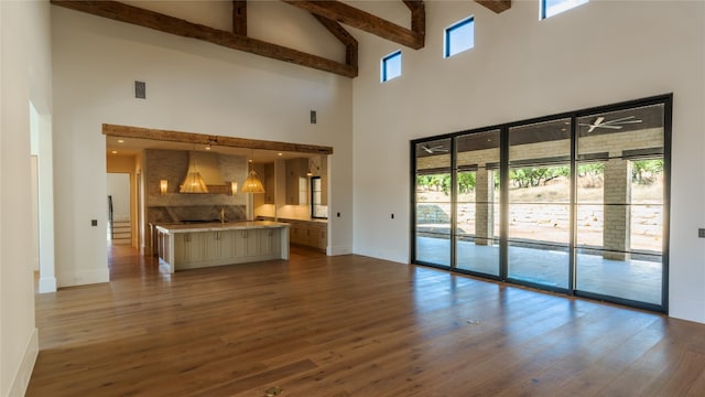 unfurnished living room with ceiling fan, sink, beamed ceiling, high vaulted ceiling, and wood-type flooring