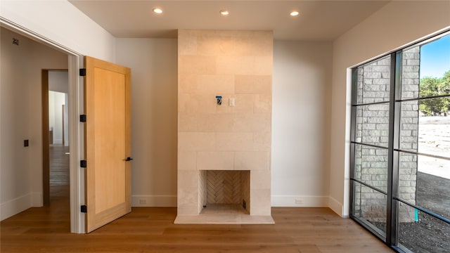 unfurnished living room with a tile fireplace and light hardwood / wood-style flooring