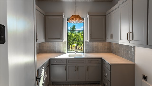 kitchen featuring decorative backsplash, pendant lighting, gray cabinetry, and sink