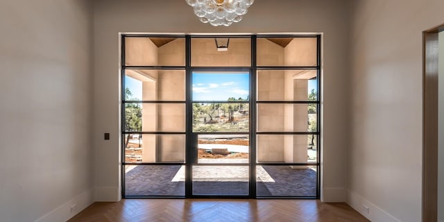 doorway with an inviting chandelier and baseboards