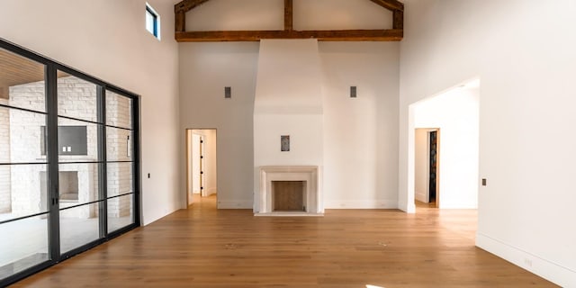 unfurnished living room with a high ceiling, baseboards, and wood finished floors