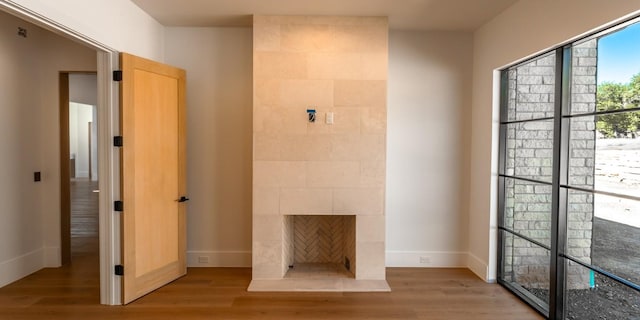 interior space with light wood finished floors, a tile fireplace, and baseboards