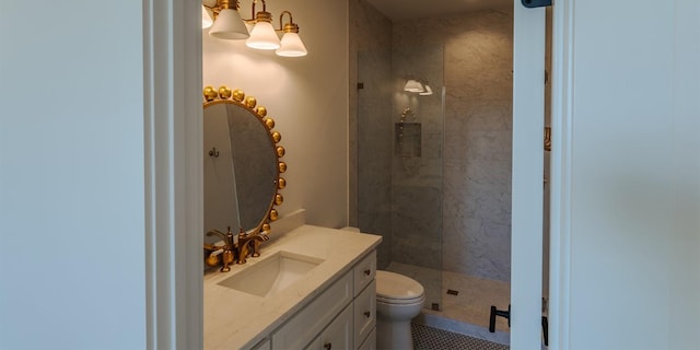 bathroom with toilet, tiled shower, and vanity