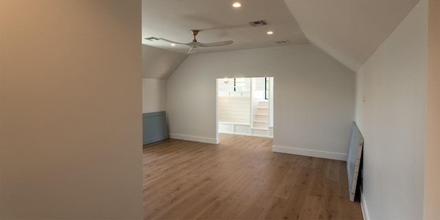 additional living space featuring light wood-style floors, visible vents, vaulted ceiling, and a ceiling fan