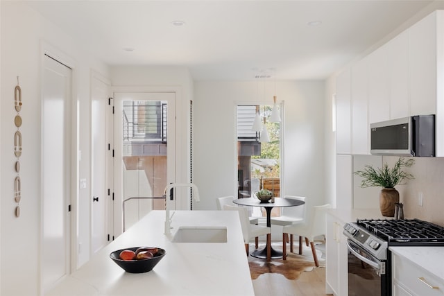 kitchen featuring light hardwood / wood-style flooring, stainless steel appliances, white cabinetry, and sink