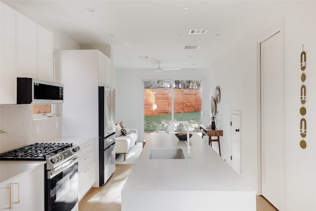 kitchen featuring white cabinets, appliances with stainless steel finishes, plenty of natural light, and sink