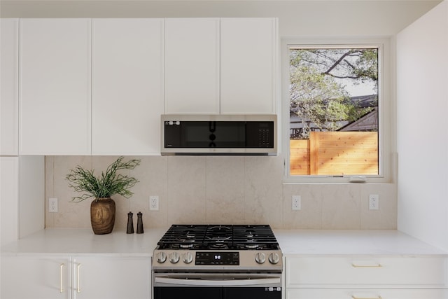 kitchen with decorative backsplash, stainless steel appliances, white cabinetry, and light stone countertops