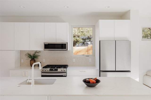 kitchen with light stone countertops, appliances with stainless steel finishes, and white cabinetry