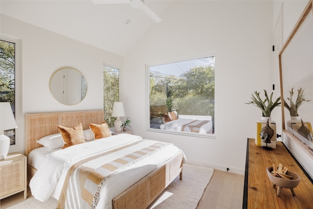 bedroom with ceiling fan, light hardwood / wood-style floors, and high vaulted ceiling