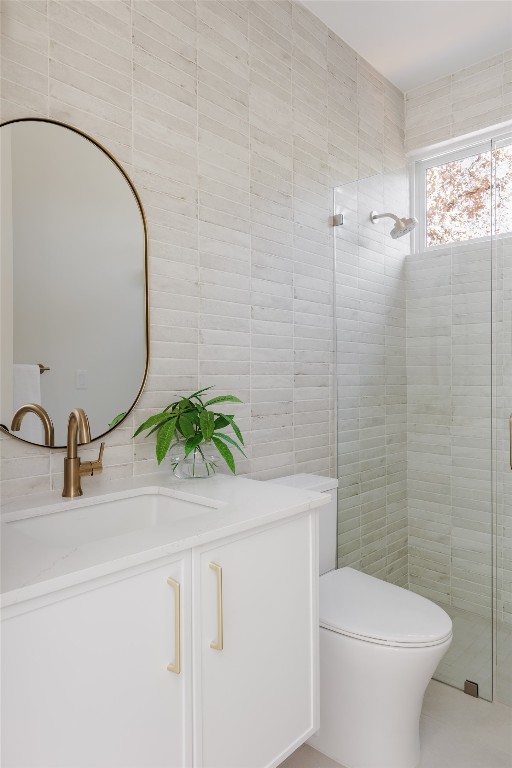 bathroom with vanity, a shower with shower door, tile walls, and toilet