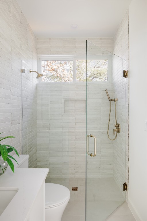 bathroom with plenty of natural light, toilet, a shower with door, and vanity