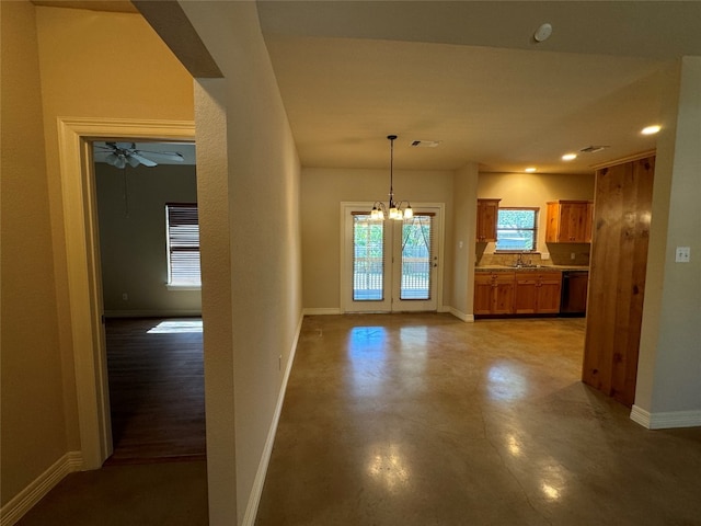 unfurnished dining area featuring french doors, ceiling fan with notable chandelier, and sink