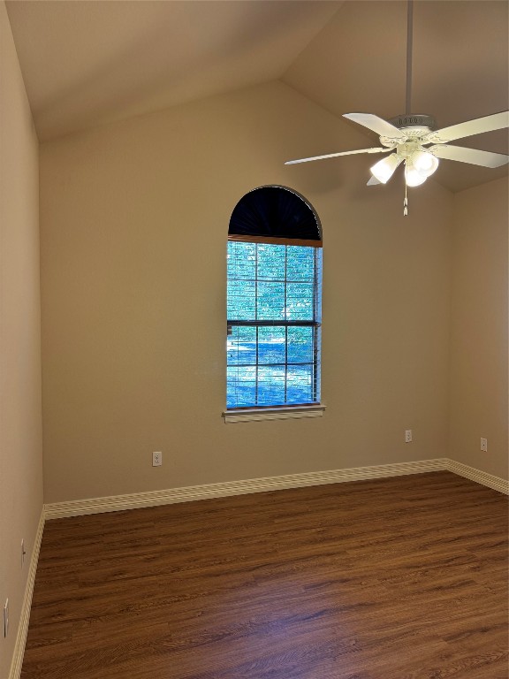 empty room with lofted ceiling, ceiling fan, and dark hardwood / wood-style floors