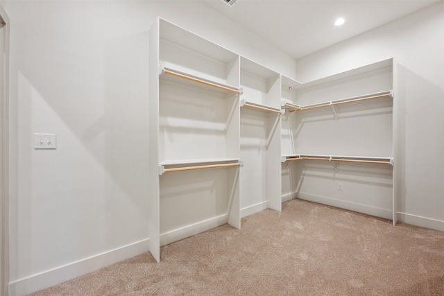 walk in closet with light carpet