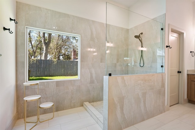 bathroom featuring tiled shower, vanity, and tile patterned flooring