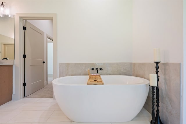 bathroom with tile patterned floors, vanity, tile walls, and a washtub