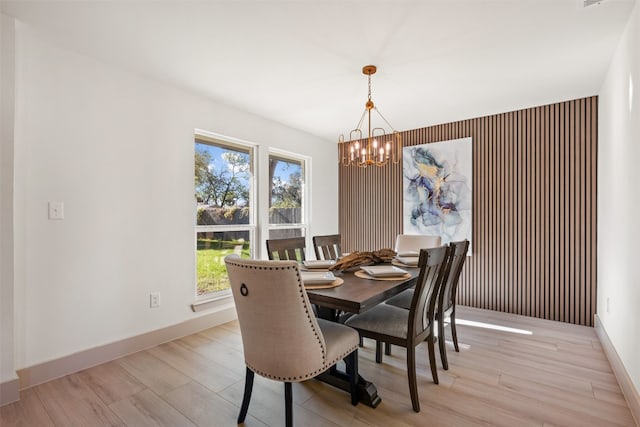 dining space with light wood-type flooring and an inviting chandelier