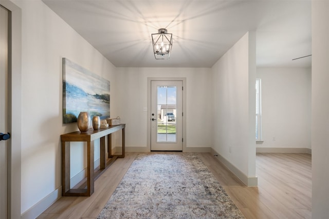 doorway with an inviting chandelier and light wood-type flooring