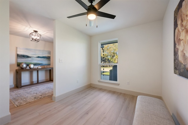 unfurnished room featuring ceiling fan with notable chandelier and light wood-type flooring