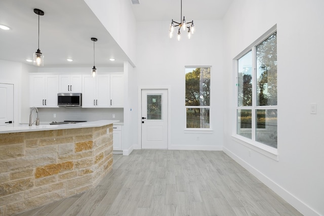 kitchen with light wood-type flooring, decorative light fixtures, white cabinetry, and a notable chandelier