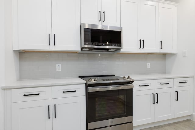 kitchen featuring backsplash, white cabinetry, light hardwood / wood-style flooring, and stainless steel appliances