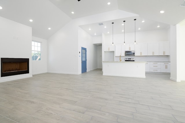 unfurnished living room featuring light hardwood / wood-style flooring and high vaulted ceiling