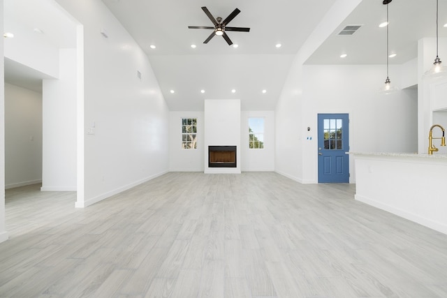 unfurnished living room with light hardwood / wood-style floors, high vaulted ceiling, and ceiling fan