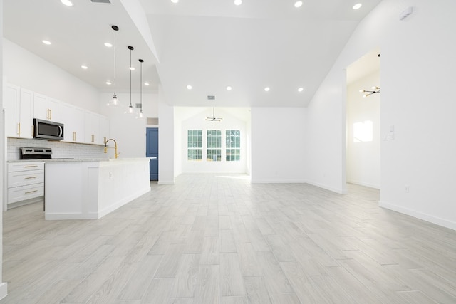 kitchen featuring pendant lighting, a kitchen island with sink, white cabinets, sink, and stainless steel appliances