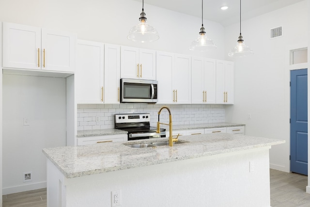 kitchen with white cabinets, appliances with stainless steel finishes, and pendant lighting