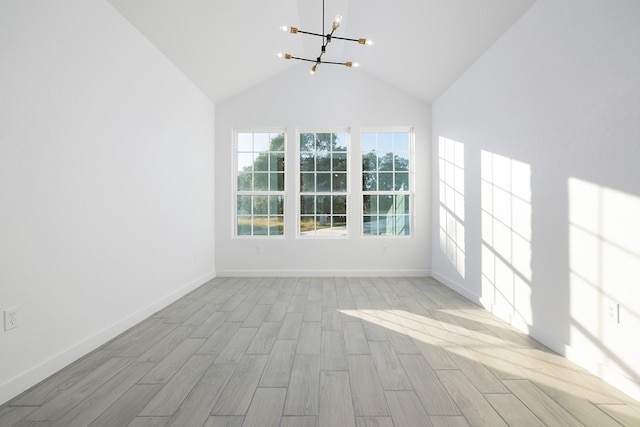 spare room featuring a notable chandelier, light hardwood / wood-style floors, and high vaulted ceiling