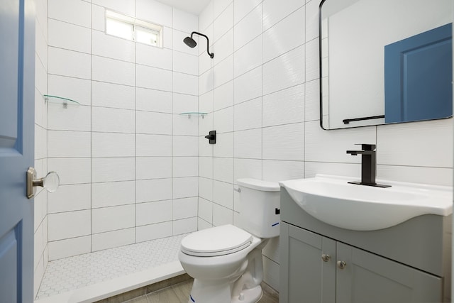 bathroom featuring tiled shower, vanity, tile walls, and toilet