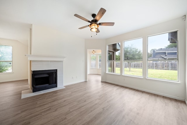 unfurnished living room featuring a tile fireplace, ceiling fan, and wood-type flooring