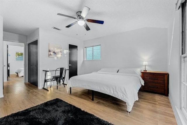 bedroom featuring ceiling fan, light hardwood / wood-style flooring, and multiple windows