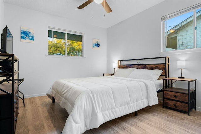 bedroom with hardwood / wood-style floors, ceiling fan, and multiple windows