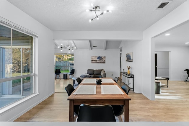 dining space with beamed ceiling, a textured ceiling, light wood-type flooring, and a notable chandelier