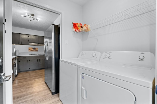 laundry area with separate washer and dryer, light hardwood / wood-style floors, and a textured ceiling