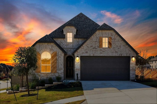 french country home featuring a garage and a lawn