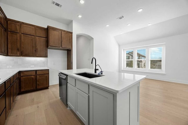 kitchen with sink, dishwasher, gray cabinetry, tasteful backsplash, and an island with sink