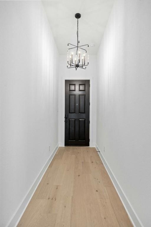 doorway to outside featuring an inviting chandelier and light wood-type flooring