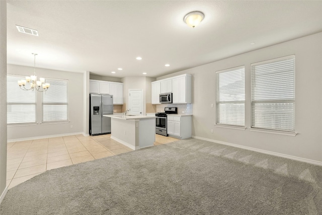 kitchen featuring stainless steel appliances, light colored carpet, decorative light fixtures, a center island with sink, and white cabinetry